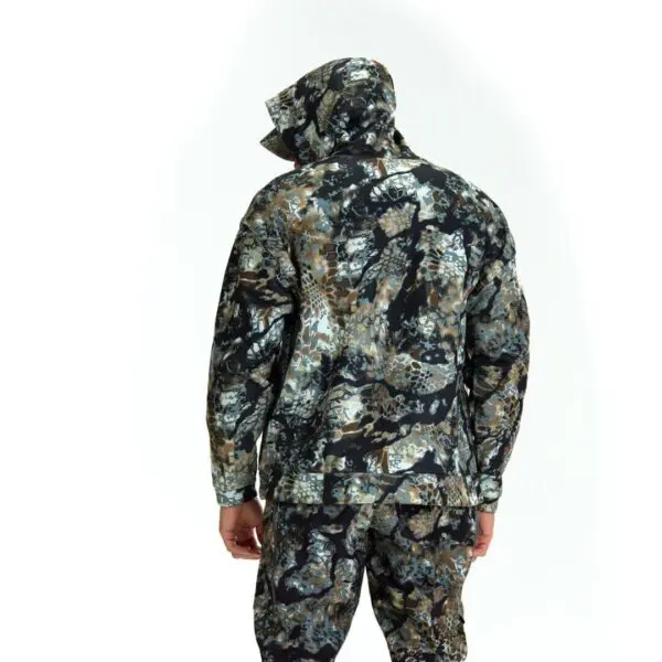 A person stands facing away from the camera, wearing a Kryptek Tartaros Hoodie Obskura Transitional and pants. The outfit features a camouflage pattern with shades of green, brown, and black. The background is white.