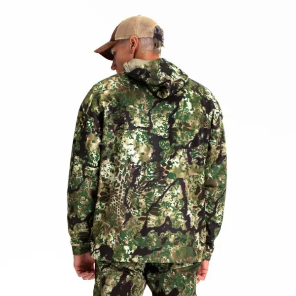A person wearing Kryptek Tartaros Hoodie Obskura Transitional, including matching pants, stands with their back to the camera. They are also wearing a beige baseball cap. The background is completely white.