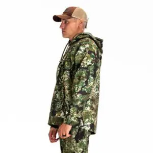 A person in profile wearing a Kryptek Tartaros Hoodie Obskura Transitional and a brown mesh-back cap stands against a plain white background. The jacket has a hood, and the individual has their hands at their sides, showcasing the side view of the outfit.