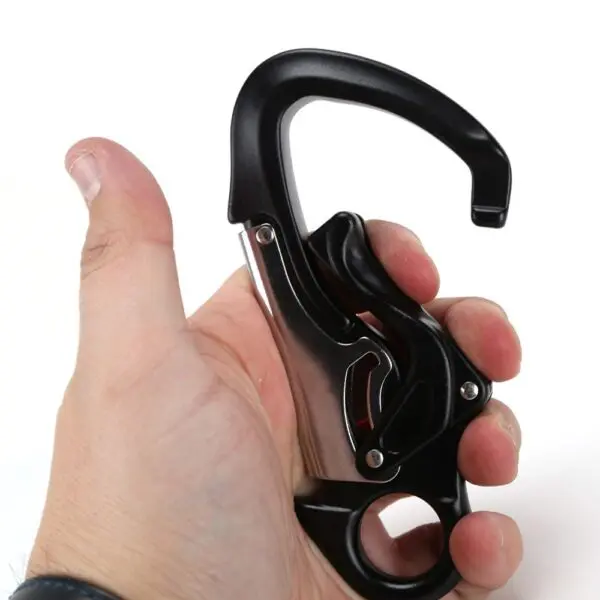A person holding an Omega Pacific Squatch Claw Aluminum Double Action Quik-Lok in their hand against a plain white background. The thumb and fingers are positioned to demonstrate the carabiner's locking mechanism.