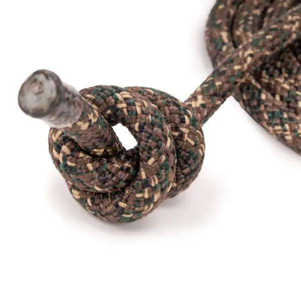 A close-up image of an Ape Canyon Outfitters 9.5mm Tree Tether tied into a complex knot. One end of the tether is threaded through the knot, and the rest of it is coiled nearby on a white surface. The tether has a mix of earthy colors, including brown, green, and beige.