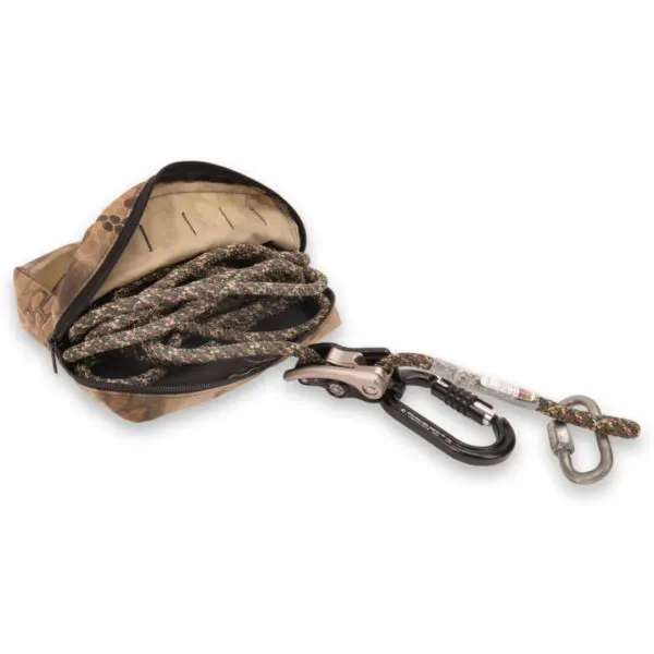 An open camouflage pouch containing an Ape Canyon Outfitters One Stick Rappel Kit with a carabiner attached at one end. The carabiner is metallic and black, connected to a second smaller carabiner via a loop, placed on a white background.