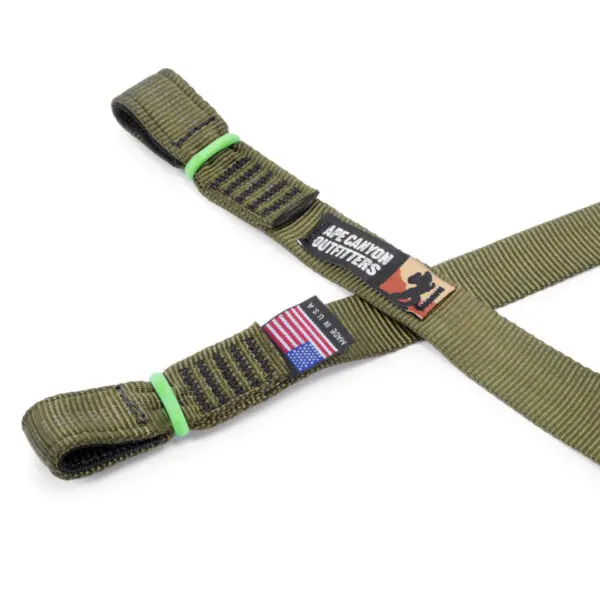 A durable, olive-green Ape Canyon Outfitters 3 Step Aider with adjustable straps, featuring an American flag patch and a label reading "AZ CANYON OUTFITTERS". The aide is designed for outdoor activities and made of robust material.