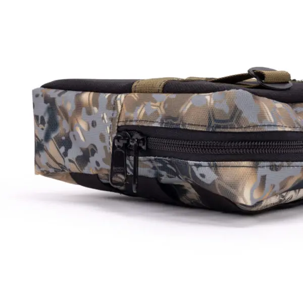 Close-up of an Ape Canyon Outfitters One Stick Saddle Pouch Obskura Skyfall featuring a carrying handle and a black zipper. The pouch has a pattern of various shades of brown, gray, and green, designed for outdoor or tactical use. The zipper runs along the side, and the handle is made of durable material.