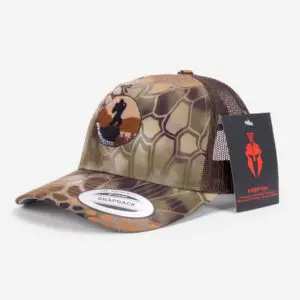 A camo-patterned Ape Canyon Outfitters Richardson Trucker Hat with a mesh back and a circular patch featuring a black horse silhouette on a brown background. The hat has a white "Snapback" sticker on the brim and a black, red, and white Kryptek brand tag attached.