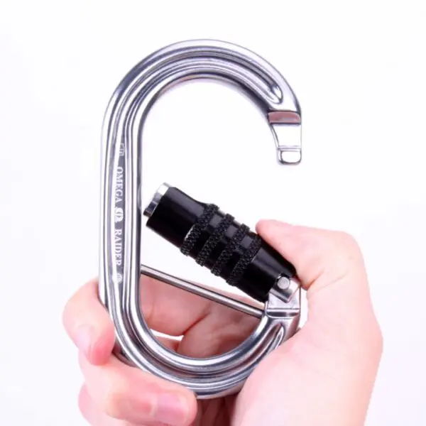 A hand holding a large, silver Omega Pacific Raider Aluminum Keylock 3-Stage Quik-Lok W/Captive Eye NFPA against a white background. The carabiner features a black screw gate mechanism for secure locking. The engraving on the side reads "OMEGA RAPIDE Q.