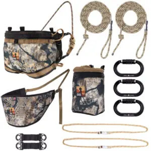 A hunting saddle kit featuring a camouflage-printed saddle, a back band, two ropes, three black carabiners, a camouflage gear pouch, and two additional gear straps. The items are arranged against a white background. This product is called the Ape Canyon Outfitters Pioneer Saddle Kit Obskura Skyfall With Cobra Buckles.