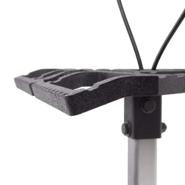 Close-up of a black, rectangular Ape Canyon Outfitters Loaded Prospector One Stick with slightly raised edges, mounted on a silver metallic stand. Two metal rods are attached to the back, likely for support or adjustment. The surface of the grate has a textured finish.