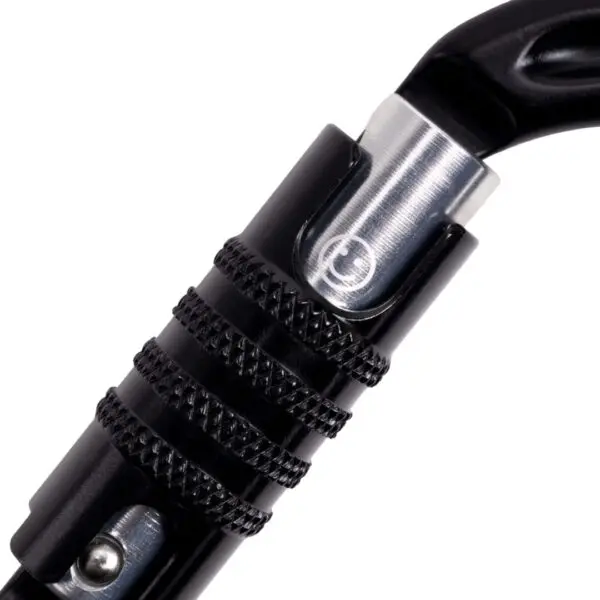 Close-up of a black Omega Pacific Raider Aluminum Keylock 3-Stage Quik-Lok NFPA - Black with a twist lock mechanism. The twist lock has a textured surface for better grip and a small circular logo is visible in the middle of the metal part of the carabiner.