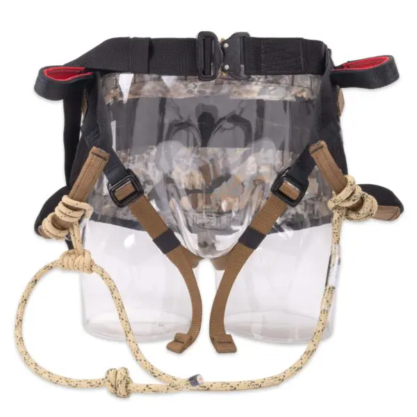 The Ape Canyon Outfitters Wood Deluxe Saddle Obskura Skyfall is designed with multiple adjustable straps and buckles. It includes leg loops, a waist belt, and carabiner loops made from durable materials. The harness is predominantly black with brown and beige accents and features sturdy ropes attached.