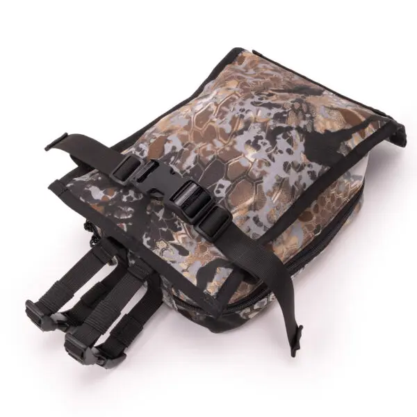 A close-up shot of an Ape Canyon Outfitters Canyon Quiver Highlander. The bag has a top flap secured with a black buckle and multiple adjustable straps hanging below it. The camouflage design features brown, grey, and black colors. The background is white.