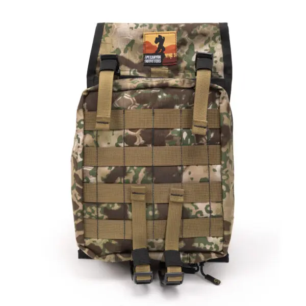 A camouflage-patterned backpack with a buckle closure on the front, beige straps, and a black top flap. A small patch with a silhouette and the text "Ape Canyon Outfitters Canyon Quiver Highlander" is displayed on the top flap.