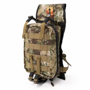 A camouflage Ape Canyon Outfitters Canyon Quiver Highlander with tan straps and a zippered front pocket. The bag features a patch with an orange and black logo at the top. The straps are adjustable, and the bag appears to be designed for outdoor or tactical use.