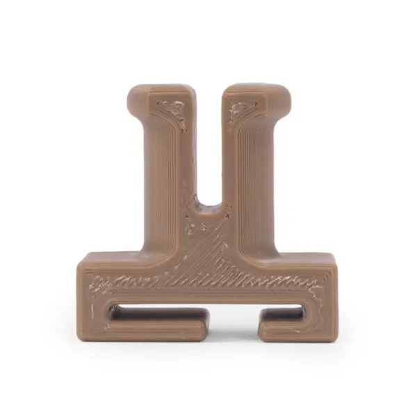 A close-up image of a small, light brown 3D-printed Ape Canyon Outfitters Retrieval Post. The object has a geometric shape resembling a capital "U" with an extended horizontal base at the bottom. The surface texture shows layers typical of 3D printing.