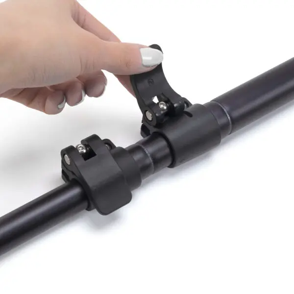 A person's hand with painted nails is adjusting a JRB Maverick Pole on a cylindrical metal rod. The rod appears to be part of a mechanical or assembly device, and the clamp is designed to secure or adjust its position.