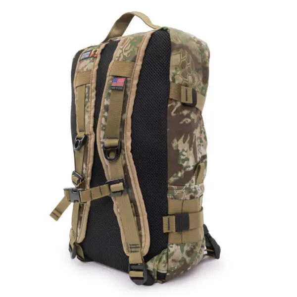 A camouflage-patterned tactical backpack featuring multiple straps, buckles, and an American flag patch on the back. The Ape Canyon Outfitters Conclave Pack Transitional has padded shoulder straps and a mesh back panel for comfort and ventilation.