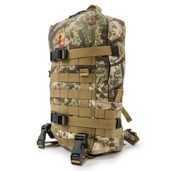 An Ape Canyon Outfitters Conclave Pack Transitional with multiple straps and buckles. The bag features a MOLLE (Modular Lightweight Load-carrying Equipment) system for attaching gear and has a patch with a logo on the front. The design is rugged and suitable for outdoor use.