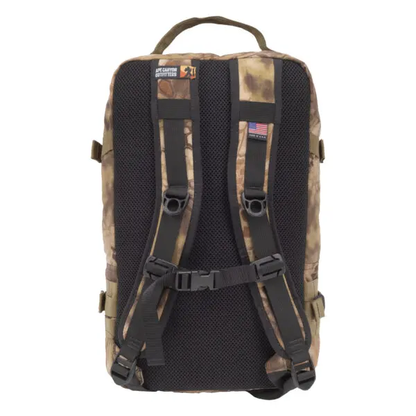 An Ape Canyon Outfitters Conclave Pack Highlander with a sturdy handle and padded shoulder straps. The back is black mesh for breathability. There is an American flag patch and a "Jet Capital" label on one of the straps. Snap buckles and adjustable straps are also visible.