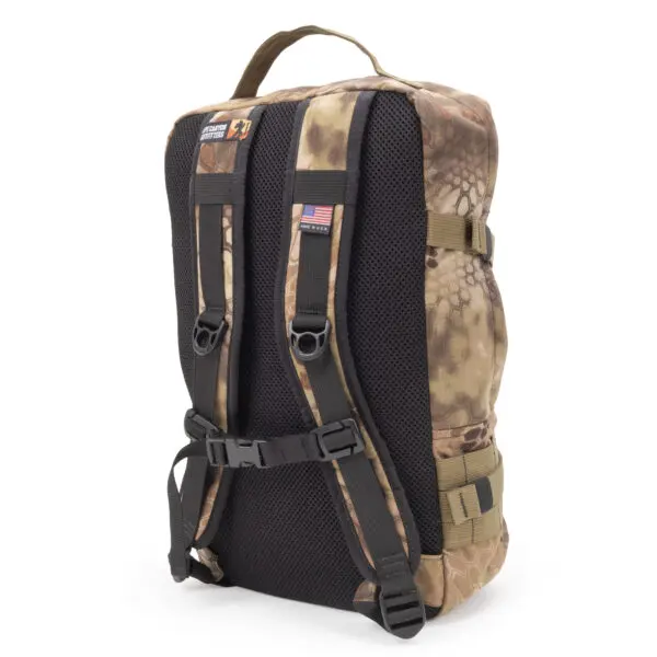An Ape Canyon Outfitters Conclave Pack Highlander is shown from the back, highlighting its padded straps and mesh back panel for comfort. The backpack also features an American flag patch on one strap and a handle on top for easy carrying.