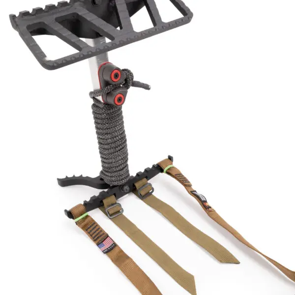The Scout One Stick features a black platform, a camo-patterned rope-wrapped handle, adjustable beige straps with metal buckles, and a serrated top for added grip. Additionally, there are two red buttons near the attachment point.