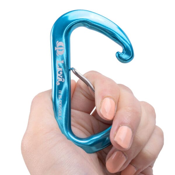A hand with light skin holding a turquoise metal hook-shaped Omega Pacific Lava Wiregate with an integrated bottle opener. The hand has neatly manicured nails painted in a light peach color. The brand name and logo are engraved on the cutter.
