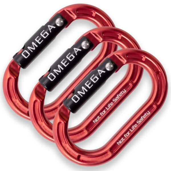 Three red, oval-shaped Omega Pacific Micro Raider Aluminum Keylock Straightgate carabiners with black locking mechanisms are arranged in a staggered stack. The word "OMEGA" is printed in white on each black section, and the phrase "Not for Life Safety" is written on the red metal body.