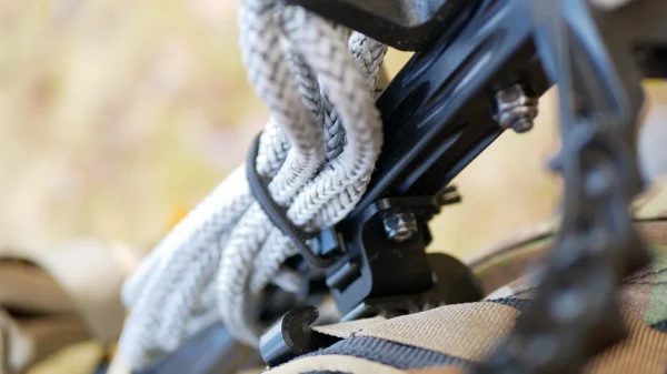 Close-up image of a One Stick Clip & Hitch. The photo focuses on the bowstring and cables, highlighting the detailed texture of the materials and some metallic components. The background is blurred, putting emphasis on the One Stick Clip & Hitch's elements in the foreground.