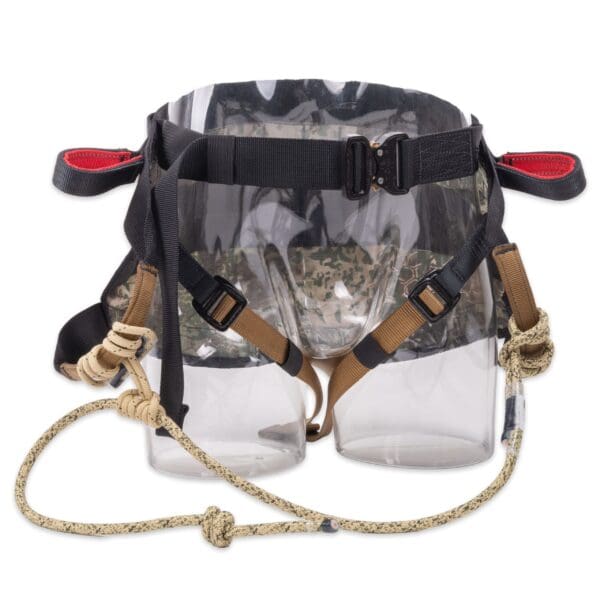 A transparent plastic saddle with straps, designed as a donkey saddlebag. The Ape Canyon Outfitters Wood Deluxe Saddle Obskura Transitional features black straps with plastic buckles, brown and beige rope handles, and red accents on the ends of the straps.